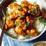 Sesame chicken in a bowl over rice.