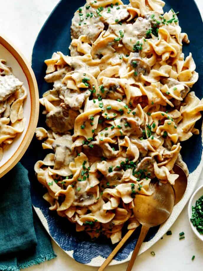 Beef Stroganoff recipe on a platter with chives on top.