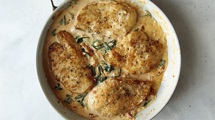 A skillet with tuscan chicken recipe in it.