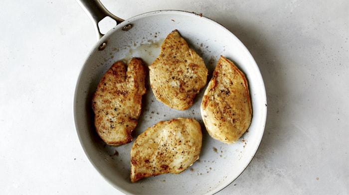 Chicken seared in a skillet with butter for tuscan chicken.