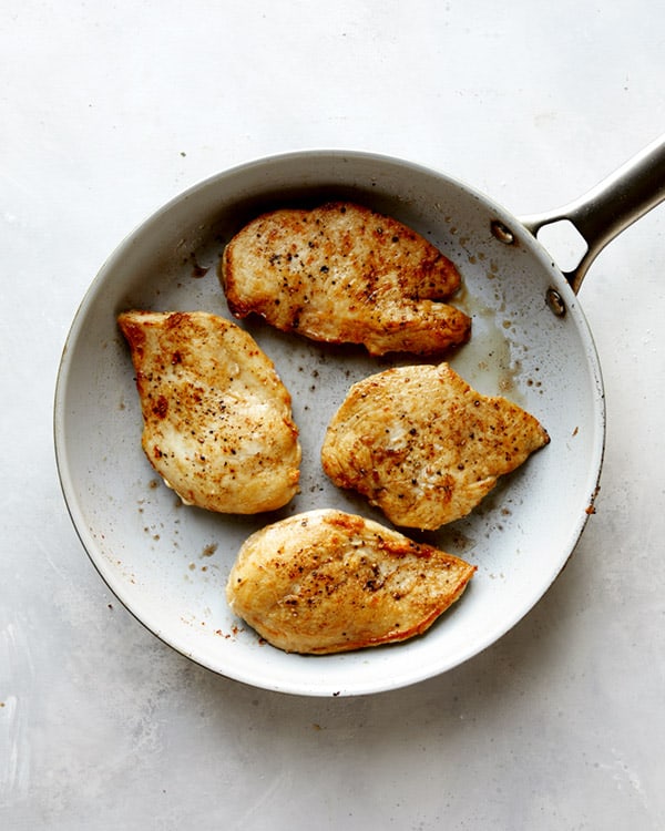Chicken seared in a skillet with butter for tuscan chicken.