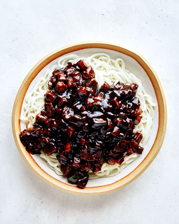 Jajangmyeon in a bowl with noodles on the bottom.