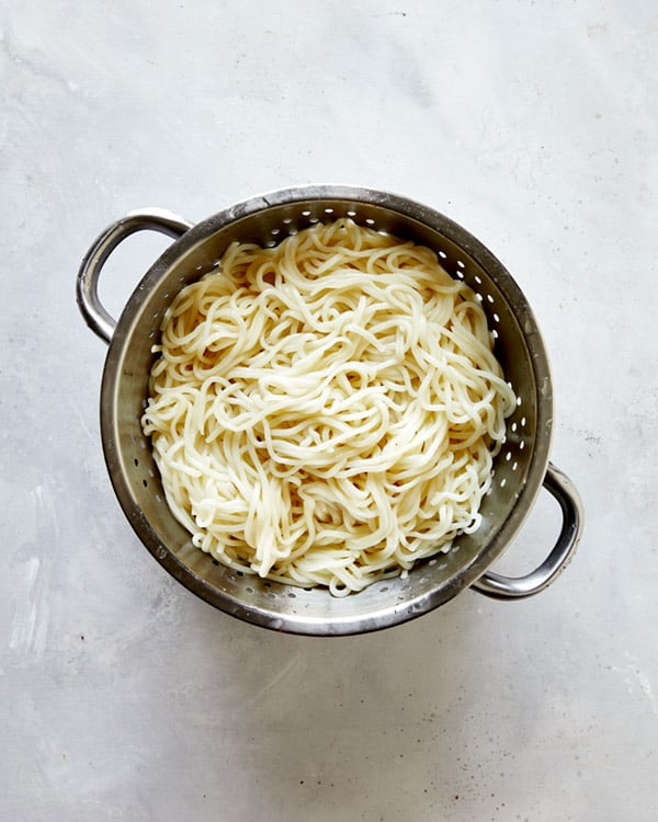 Udon noodles cooked in a colander.