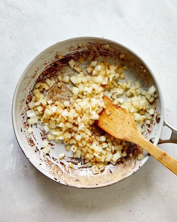 Onions and garlic in a skillet cooking to make Jajangmyeon.