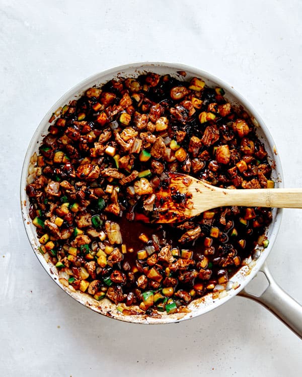 Black bean paste in a skillet mixed with veggies and meat.