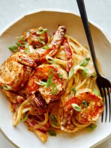 Cajun shrimp pasta recipe in a bowl with a fork on the side.