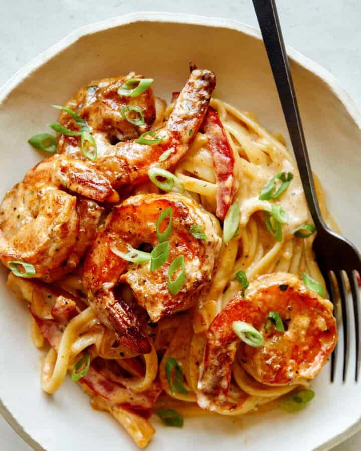 Cajun shrimp pasta recipe in a bowl with a fork on the side.