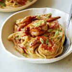 A bowl of cajun shrimp pasta recipe with green onions.