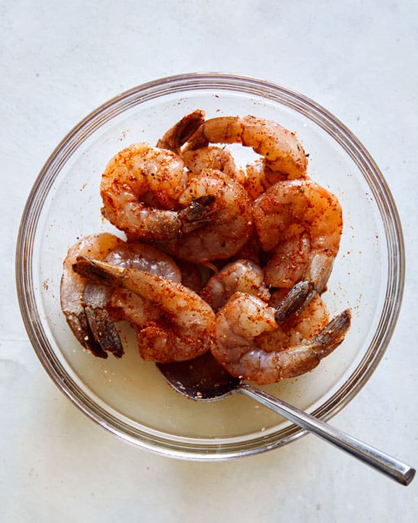 Shrimp in a bowl mixed with seasoning.