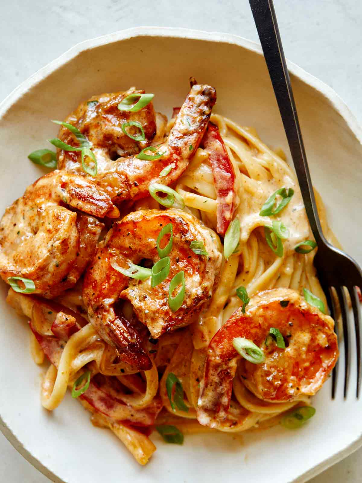 Cajun shrimp pasta recipe in a bowl with a fork on the side. 