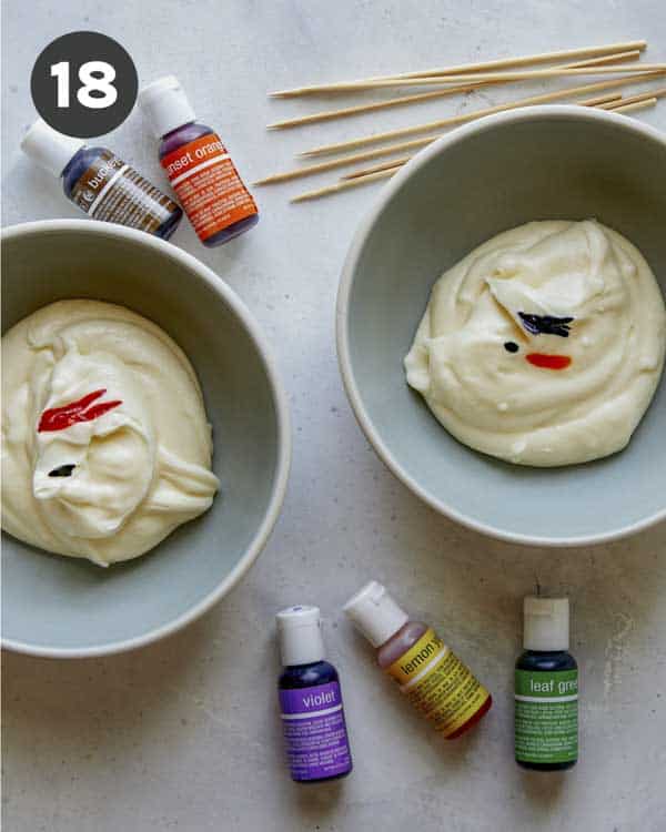 Frosting in two bowls being colored with food coloring.