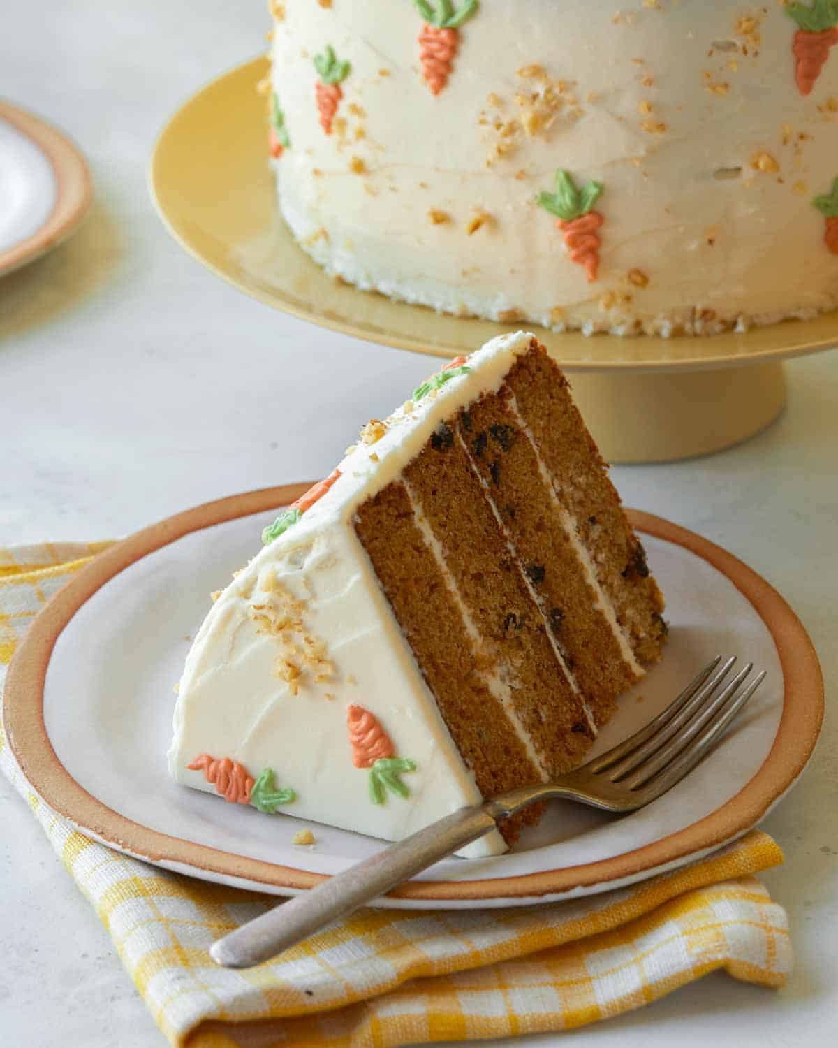 A slice of carrot cake with cream cheese frosting on a plate.