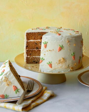 Carrot cake recipe on a cake stand with a slice out.