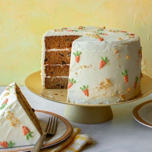 Carrot cake recipe on a cake stand with a slice out.