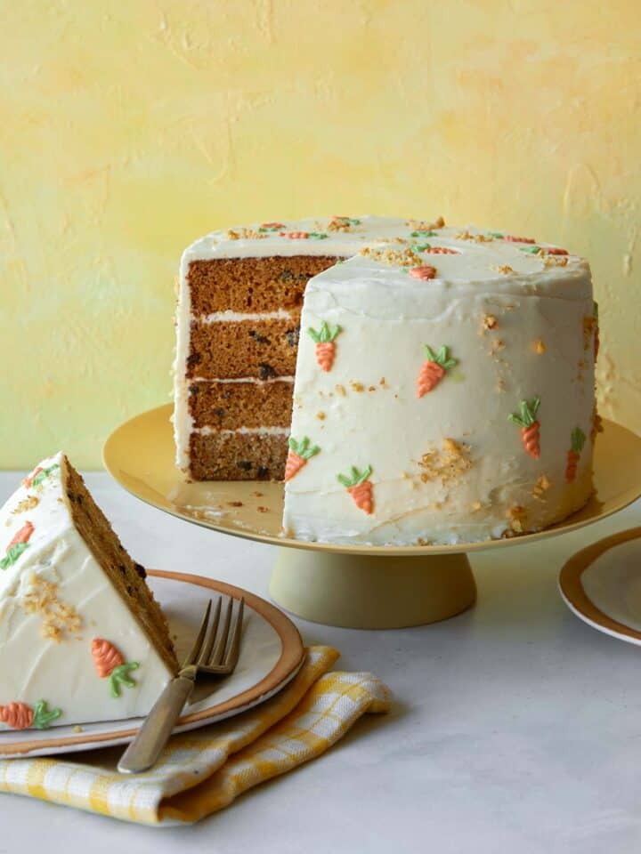 Carrot cake recipe on a cake stand with a slice out.