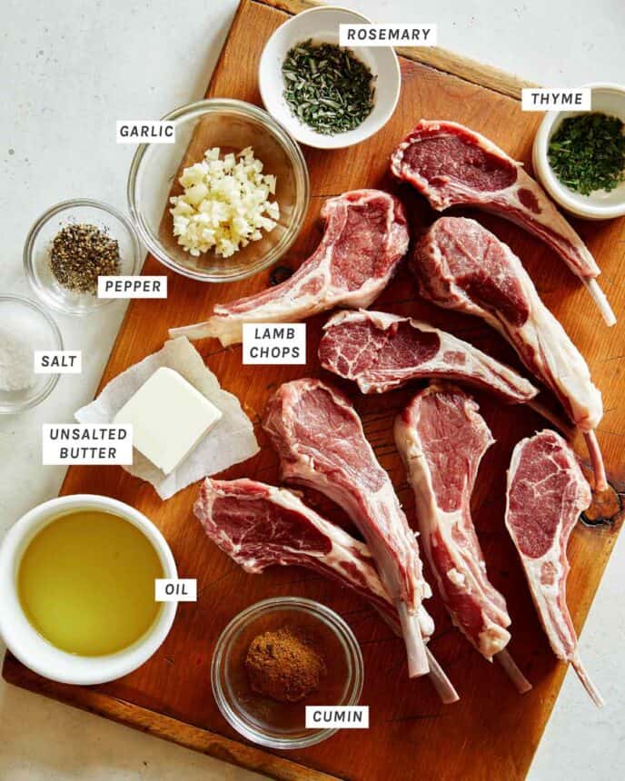 Lamb chops on a cutting board with rub ingredients around them.