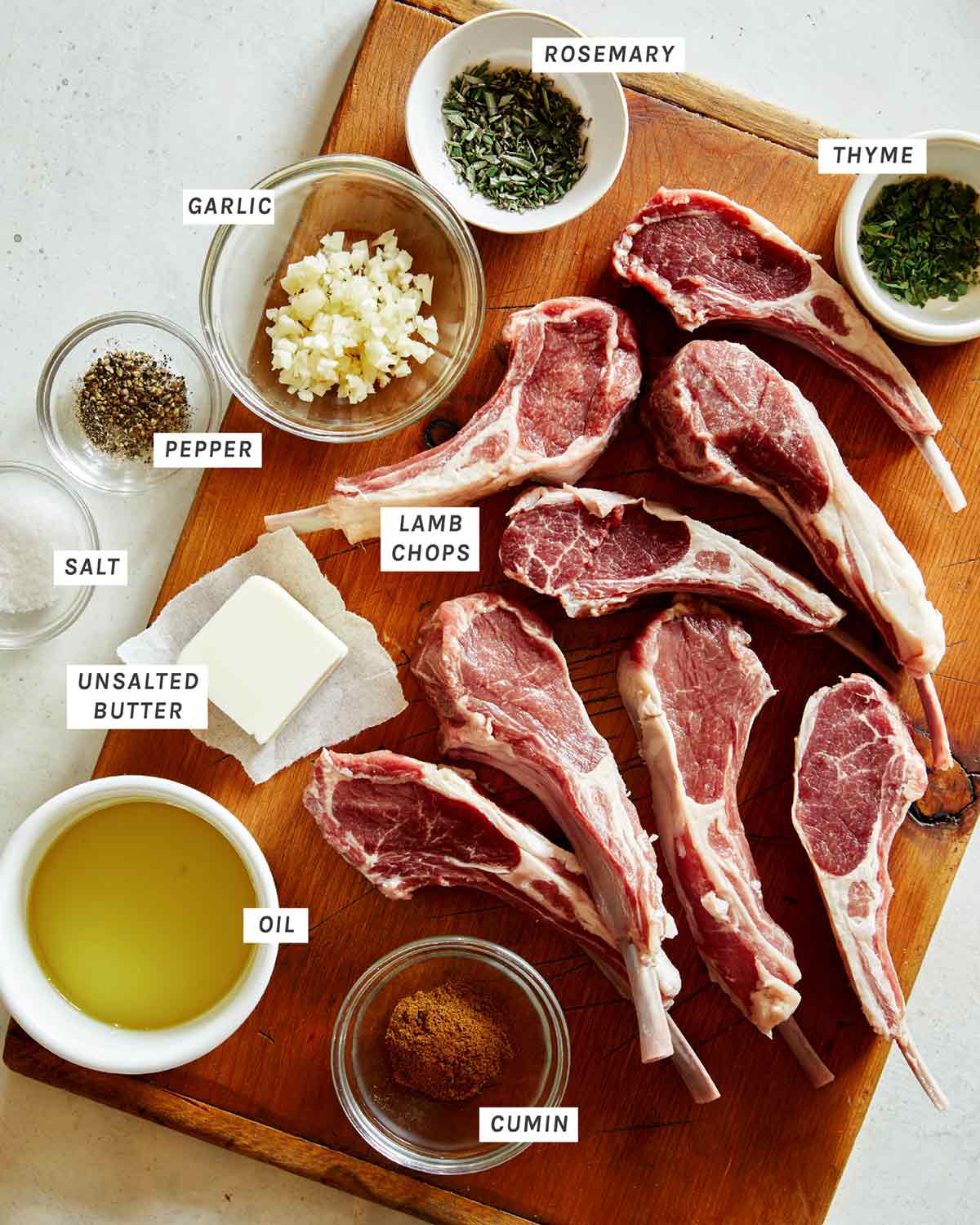 Lamb chops on a cutting board with rub ingredients around them. 