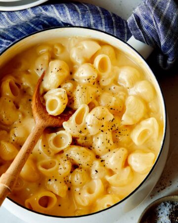 Stovetop mac and cheese in a pot with a wooden spoon in it.