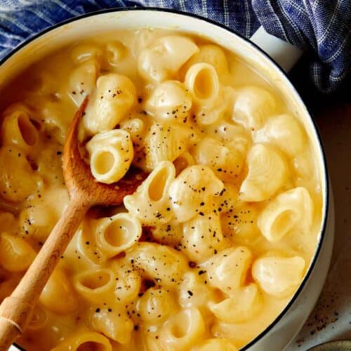 Stovetop mac and cheese in a pot with a wooden spoon in it.
