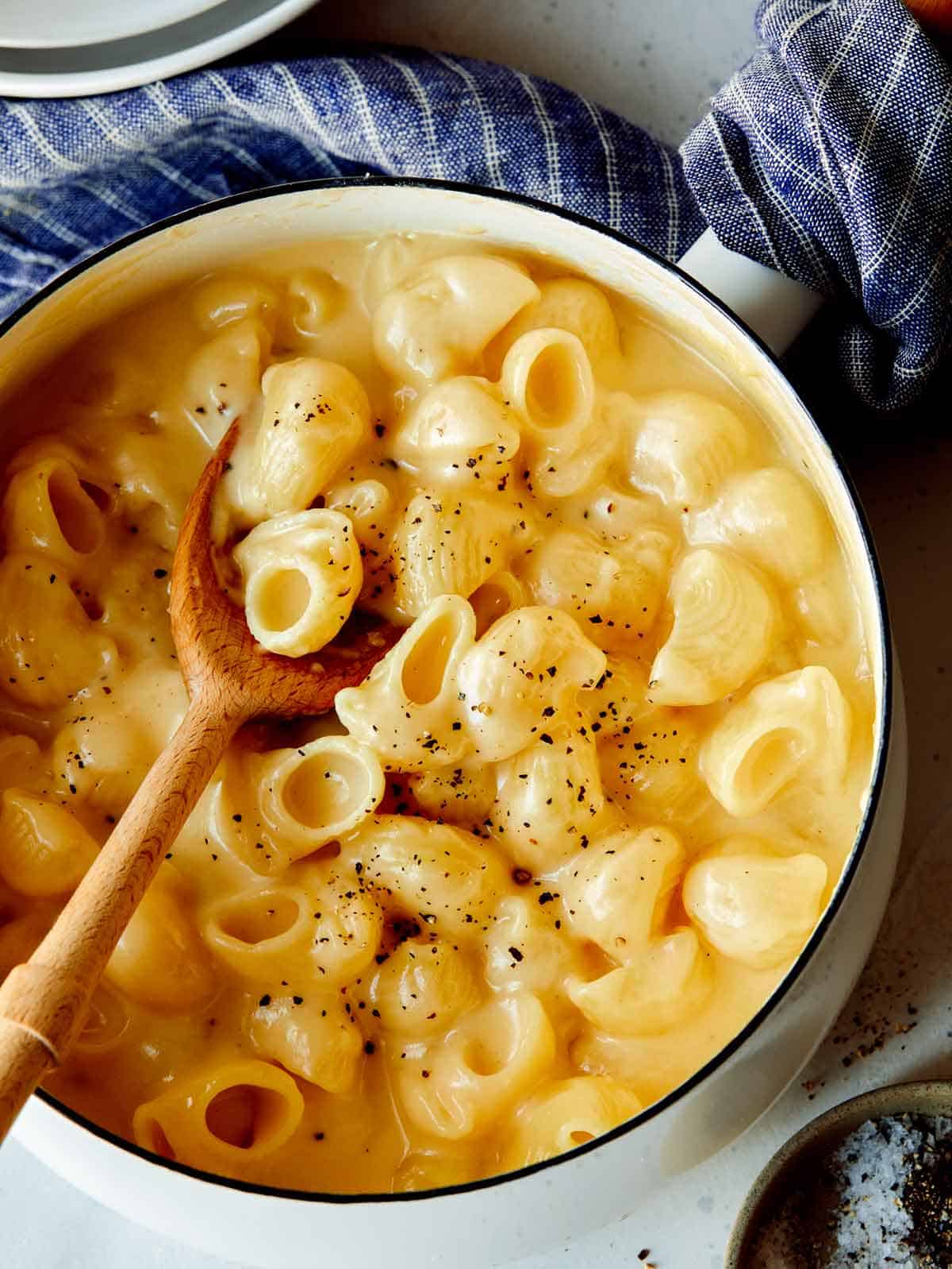 Stovetop mac and cheese in a pot with a wooden spoon in it. 