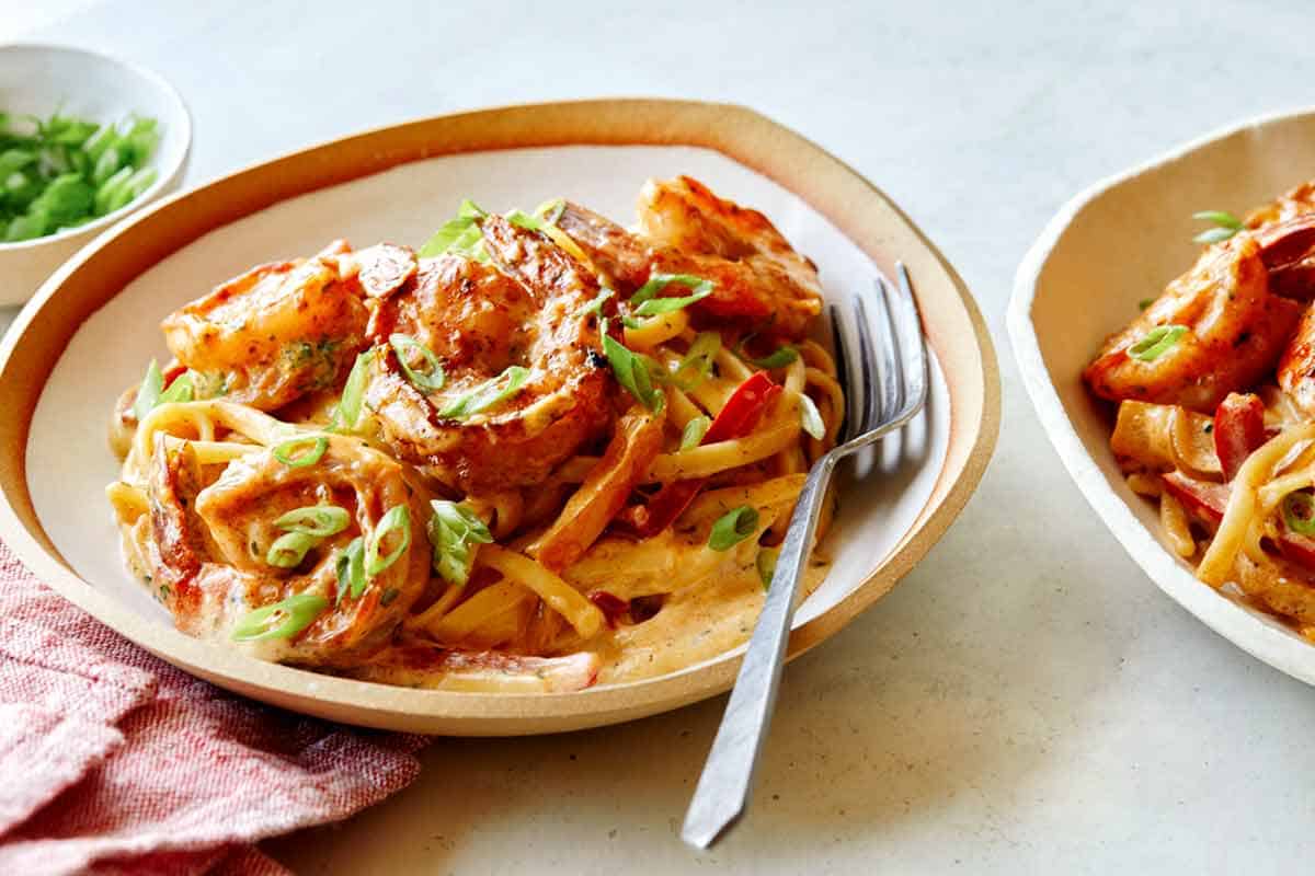 Two bowls of cajun shrimp pasta with forks on the side. 