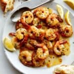 Shrimp scampi recipe on a plate with lemon wedges.