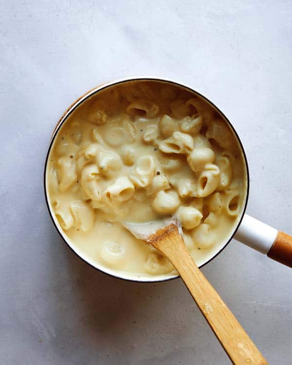 Stovetop mac and cheese  in a skillet with wooden spoon. 