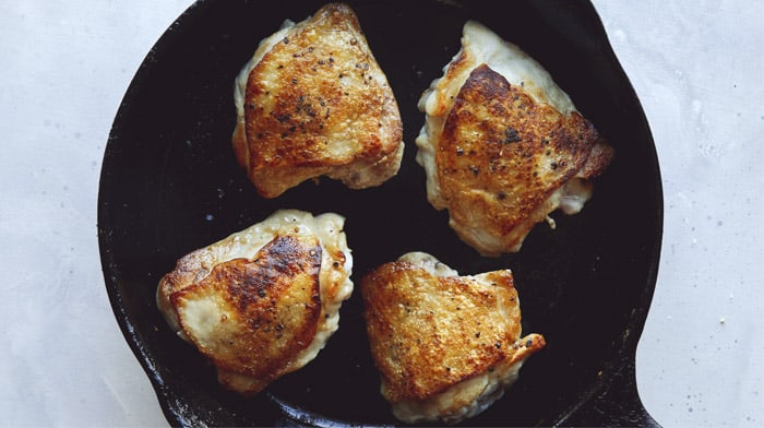 Chicken thighs in a skillet.
