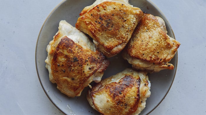Cooked chicken thighs resting on a plate.