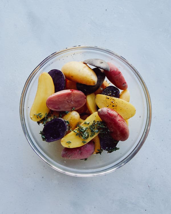 Fingerling potatoes in a bowl tossed with some ingredients.