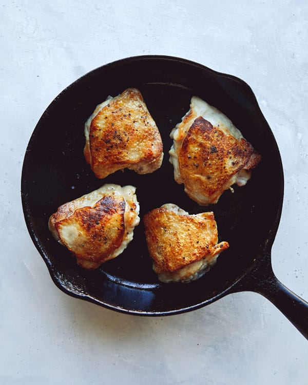 Chicken thighs in a skillet.