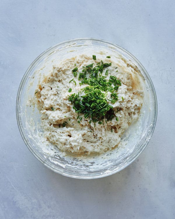 Drop biscuit dough in a bowl adding chives.