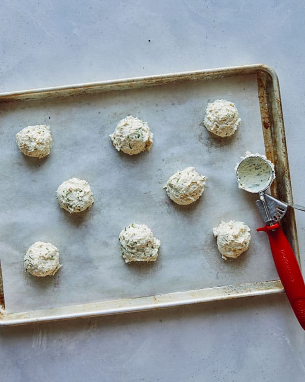 Drop biscuit dough scooped onto a parchment lined baking sheet.