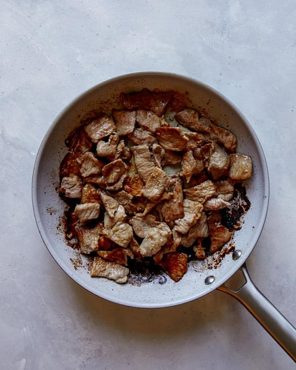 Pork cooking in a skillet for pad see ew. 