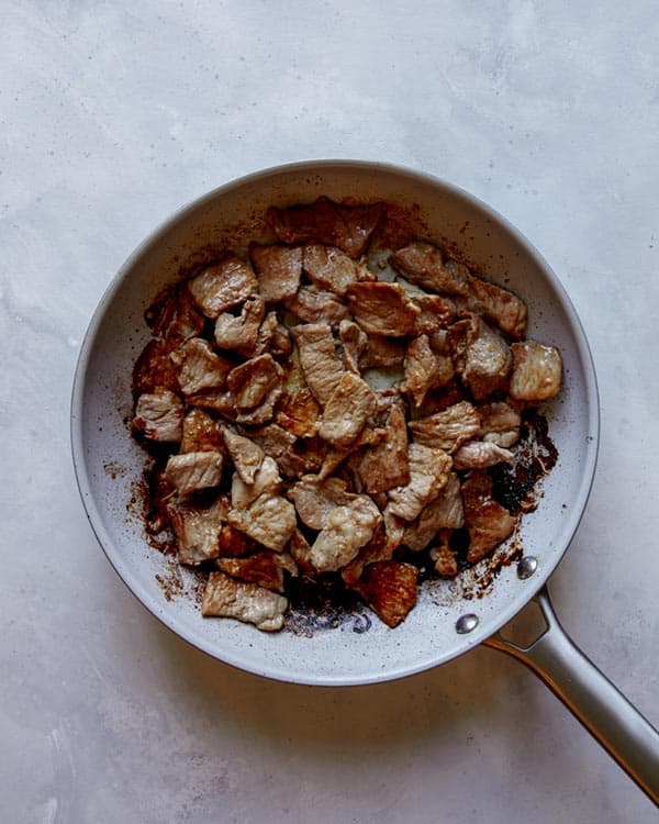 Pork cooking in a skillet for pad see ew.