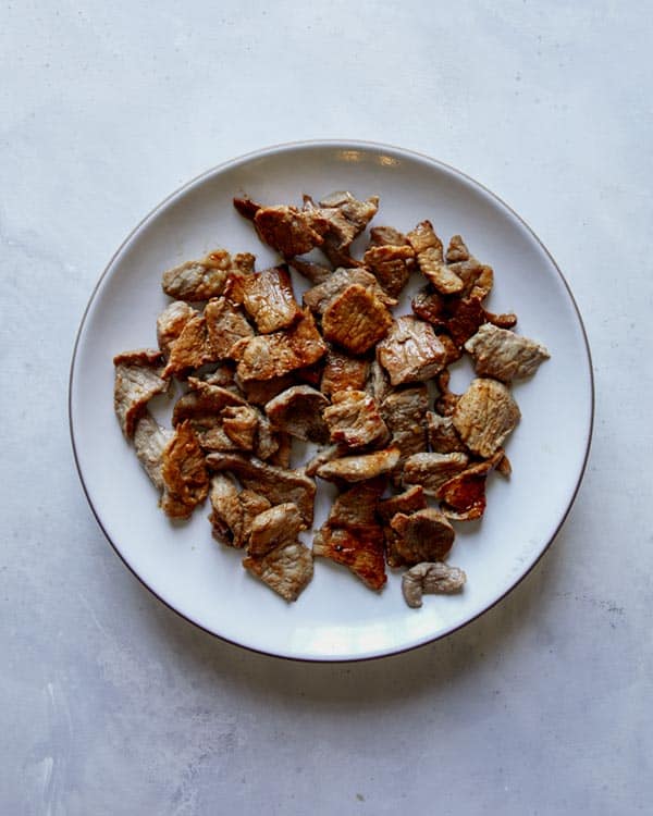Cooked pork on a plate for pad see ew.