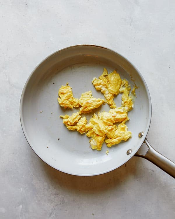 Eggs being cooked in a skillet for pad see ew.