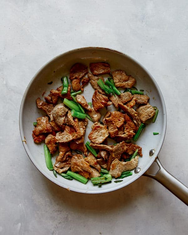 Pork and broccoli in a skillet.
