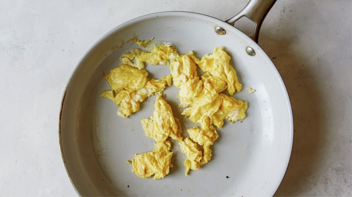 Eggs being cooked in a skillet for pad see ew.