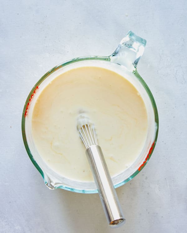 Eggs and cream whisked together in a bowl.