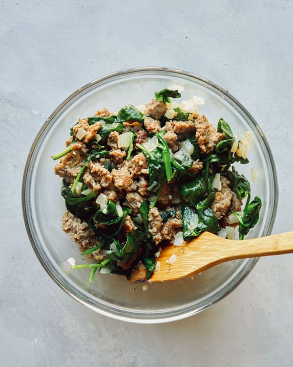 Sausage and spinach and other ingredients for the filling of a strata.