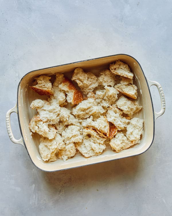 Torn bread in a baking dish for the base layer of a strata.
