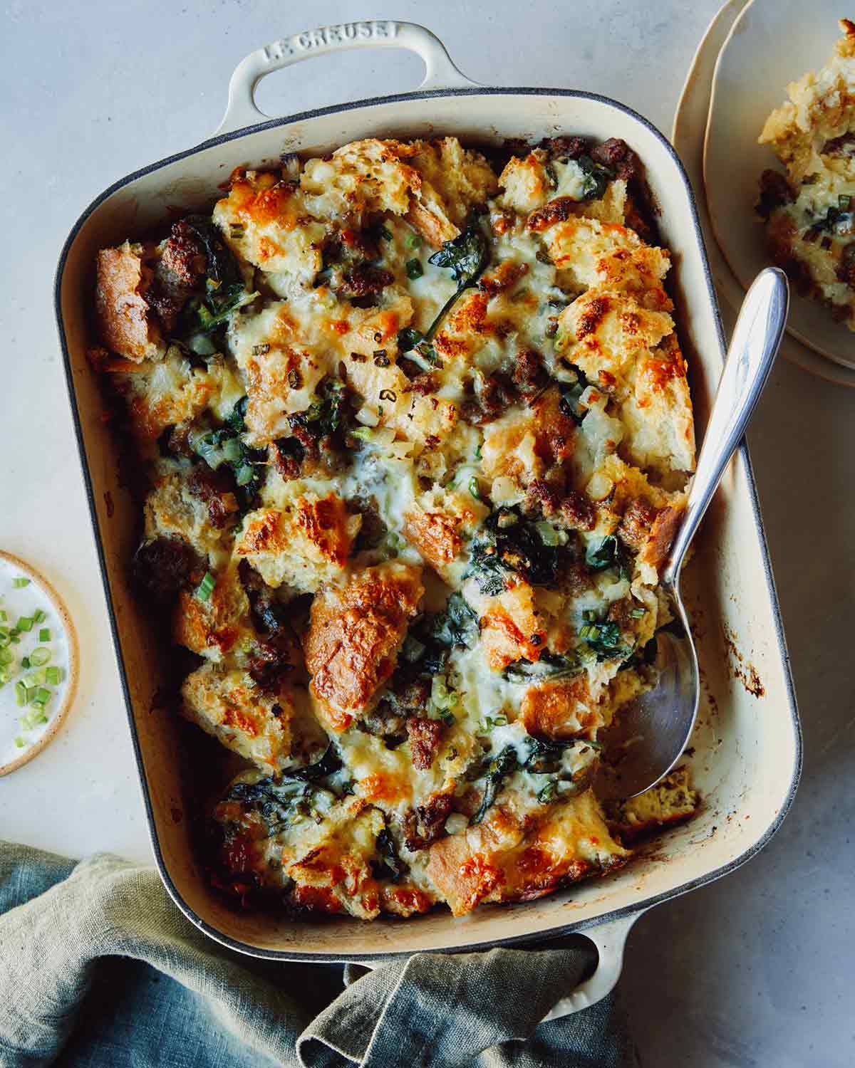 Sausage strate recipe in a baking dish with green onions on the side. 