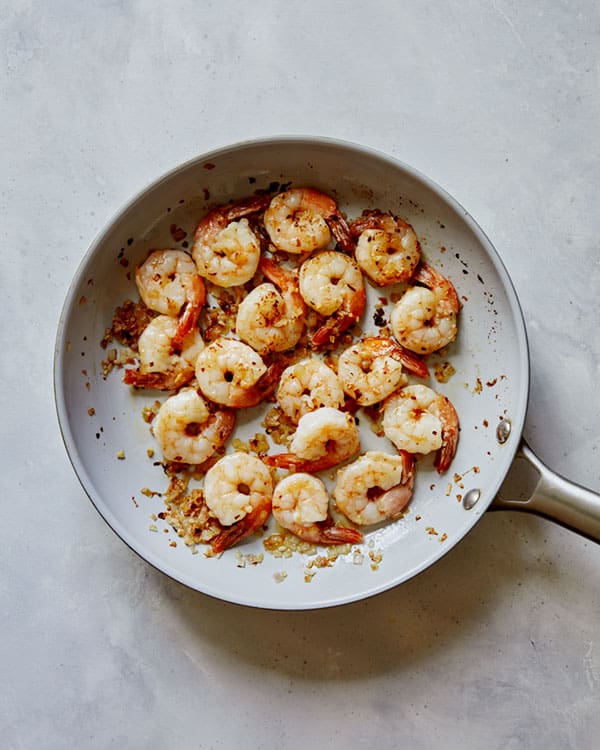 Shrimp being cooked in a skillet for shrimp scampi.