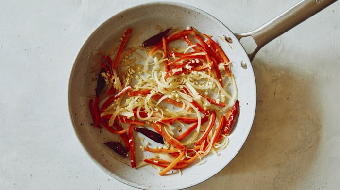 Peppers with ginger and garlic cooking in a skillet.