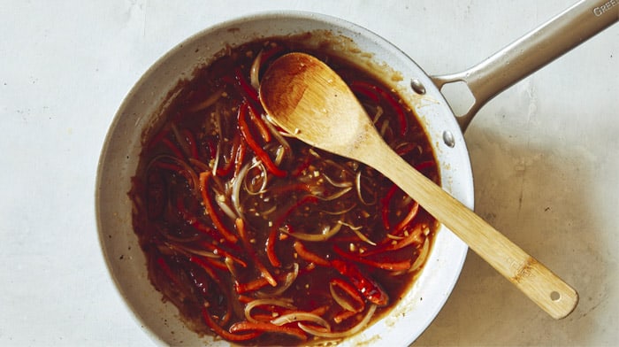 Szechuan beef in a skillet cooking with sauce.