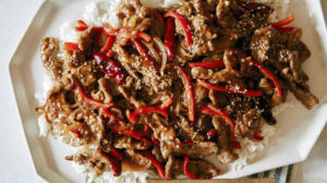 Szechuan beef over rice on a platter.