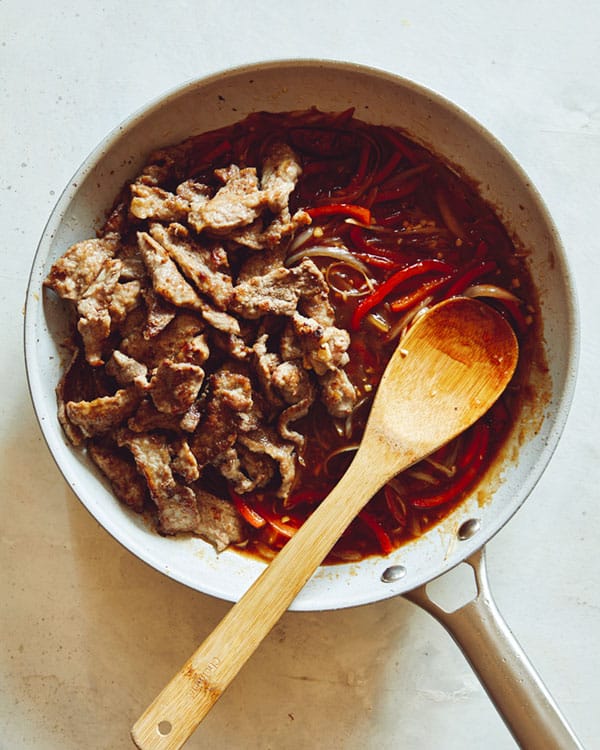Szechuan beef sauce with peppers in a skillet.