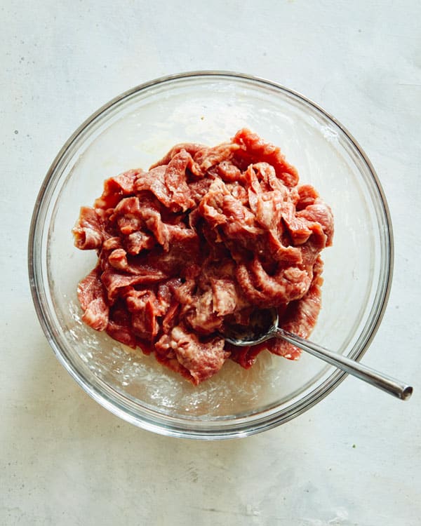 Szechuan beef mixed with cornstarch in a bowl. 