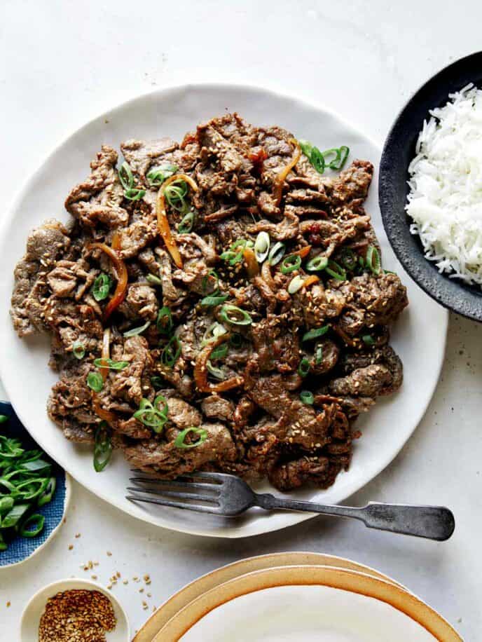 Korean beef bulgogi with rice on the side and sesame seeds.